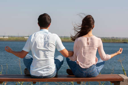 Morning meditation. Beautiful young couple in white clothing meditating outdoors together and keeping eyes closed. Portraitの写真素材