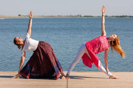 Two mature women keeping fit by doing yoga in the summer. Portraitの写真素材