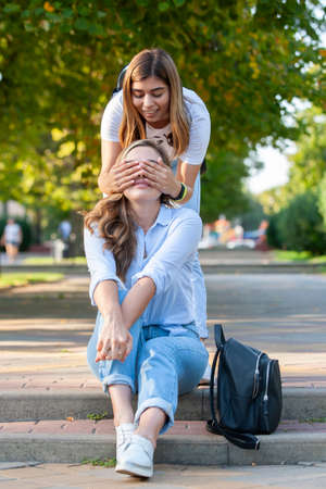 Two beautiful young girls are sitting on the steps. Girlfriends are resting in the city in the summer. Portraitの写真素材