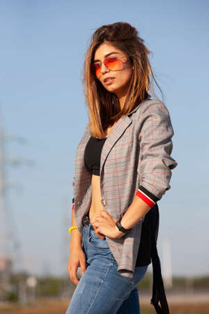 Happy joyful young woman posing by river and looking away. Portrait of cheerful lady in casual standing outside, keeping hands in jeans pocket and smiling. Outdoor portrait conceptの写真素材