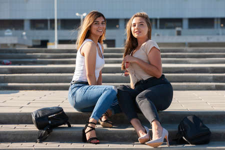 Beautiful girls in a city. Stylish ladies sitting on a stairs. Portrait.の写真素材