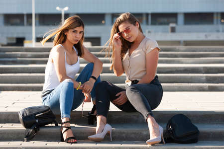 Beautiful girls in a city. Stylish ladies sitting on a stairs. Portrait.の写真素材