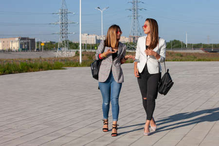 Two young happy women walking in the summer city. Portrait.の写真素材