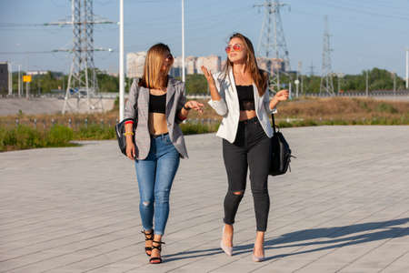 Two young happy women walking in the summer city. Portrait.の写真素材