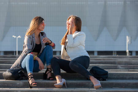 Beautiful girls in a city. Stylish ladies sitting on a stairs Portrait.の写真素材