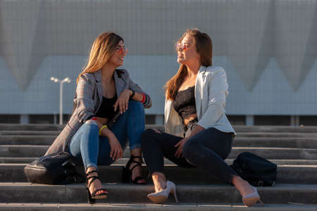 Beautiful girls in a city. Stylish ladies sitting on a stairs Portrait.の写真素材