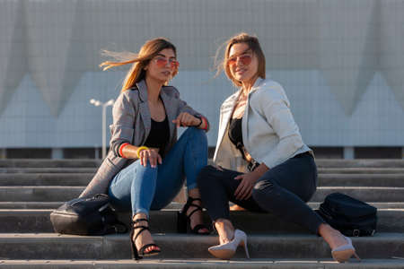 Beautiful girls in a city. Stylish ladies sitting on a stairs Portrait.の写真素材