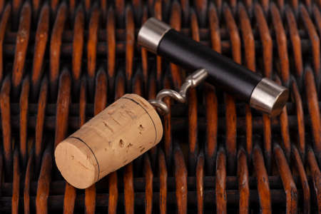 Opening a wine bottle with a cork screw in a restaurant. Against the background of a wicker basket...