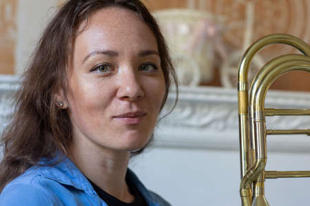 Close portrait of a young red-haired woman in a green park with a saxophone. Portraitの写真素材