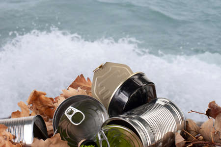 Still life of an empty used tin can with lid and pull waste on forest floor as an environmental...