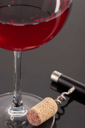 High angle view with shallow depth of field of a glass of red wine with a corkscrew. Close-up.の写真素材