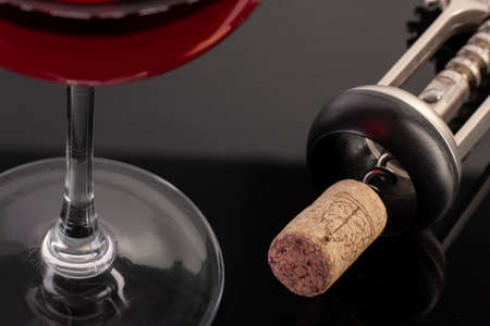 High angle view with shallow depth of field of a glass of red wine with a corkscrew. Close-up.の写真素材