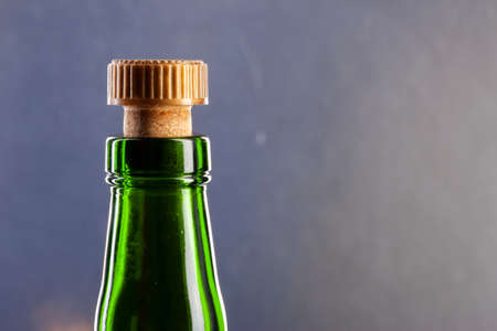 Green wine bottle with cork on dark background, close-up view. Limited depth of field.の写真素材