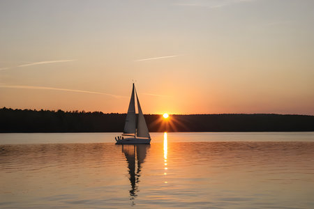 A sailboat gliding on a calm lake with the sun setting behind it, showcasing the peaceful and scenic side of summer. ai generativeの素材