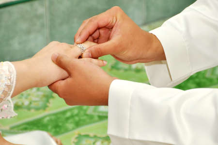 Wedding ceremony moment where the groom places the wedding ring on the brides finger.の写真素材