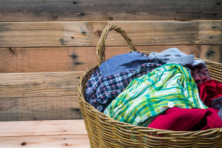 Clothes in a laundry wooden basket isolated on wooden backgroundの写真素材