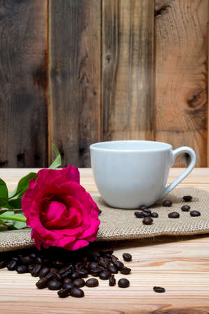 Pink rose coffe cup and coffee beans on wooden tableの写真素材