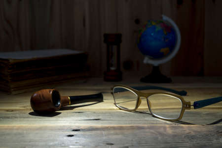 eyeglass and tobacco pipe on wooden table. still life style.の写真素材