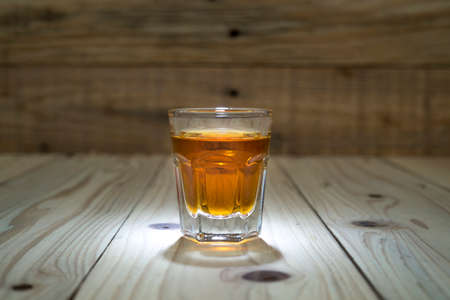 Cocktail Glass with brandy or whiskey - Small Shot. Isolated on wooden backgroundの写真素材
