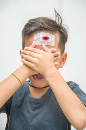 Child gets injury on the forehead has a plaster on the wound , He's cryingの写真素材
