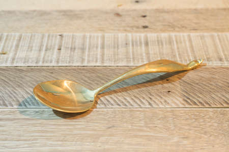 brass ladle isolated on wooden tableの写真素材