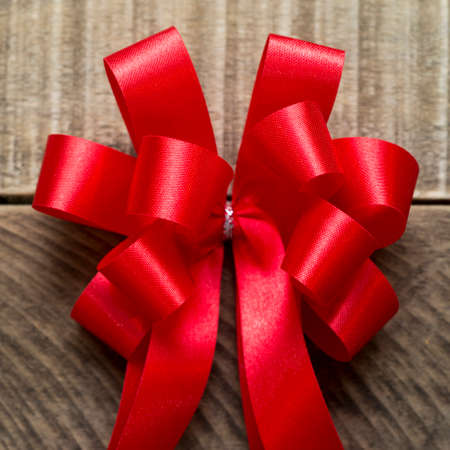 Red bow on wooden background