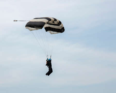 Parachutist on blue sky preparing for landing