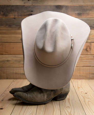 Cowboy boot and western hat on wooden background.