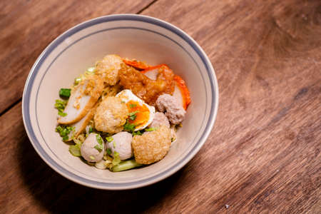 Spicy noodle with boiled egg and grilled red pork. Chinese egg noodles topping slice roasted pork, meatballon plate.の写真素材