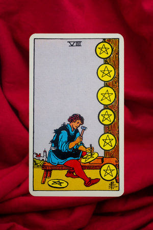Yala Province, Thailand, June 1, 2022- Eight of Pentacles Tarot Card of Rider Waite deck on red fabric background.のeditorial素材