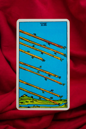 Yala Province, Thailand, June 1, 2022- Eight of Wands Tarot Card of Rider Waite deck on red fabric...