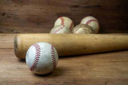 Close up old baseball and wooden baseball bat on a woodeb table. select focus.の写真素材