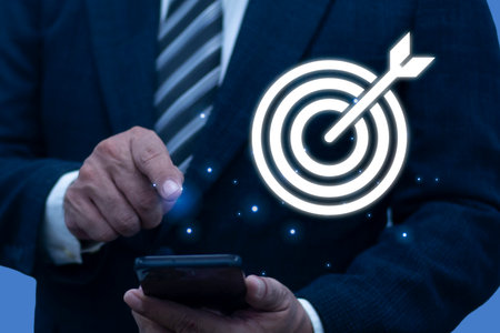 Businessman hand using smartphone touching to target dart board icon with arrow for setup and...
