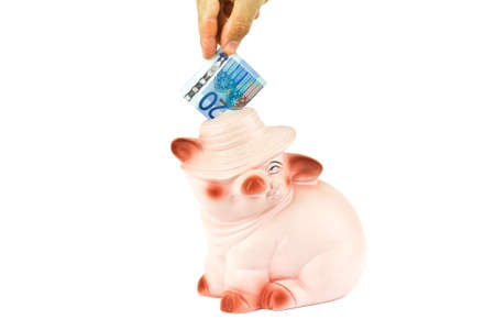 Male hand putting money into piggy bankの写真素材