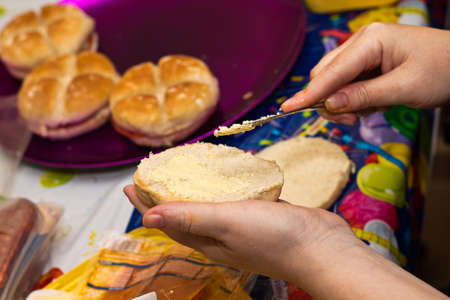Woman spreading butter on bread for a birthday party snack