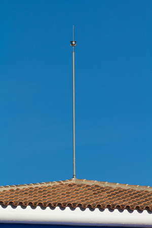 Lightning conductor on a tile roof with a blue skyの写真素材