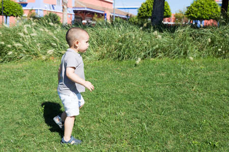 Side view of toddler boy walking on the grass in the parkの写真素材