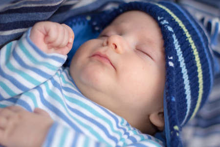 Newborn baby boy with striped hat and pajama sleeping on a blue blanket. Shallow Focusの写真素材