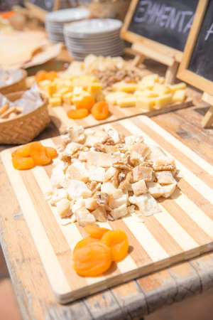 Several kinds of cheese served with dried apricots and walnuts on vintage wooden tableの写真素材