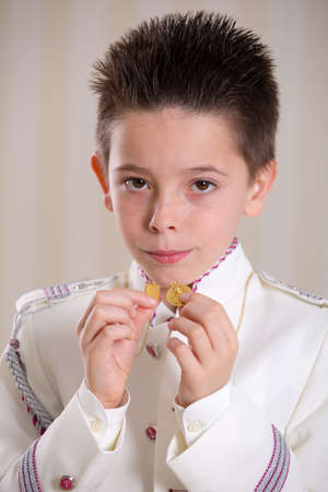 Closeup of a young boy showing his medals and looking at camera in his First Holy Communionの写真素材