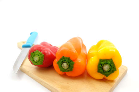 Mixing sweet peppers  on wooden plate with knife
