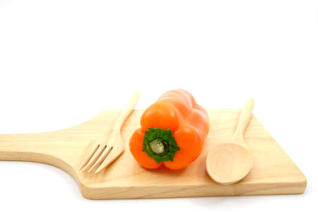 Orange sweet peppers on wooden plate with wooden spoons and wooden forkの写真素材