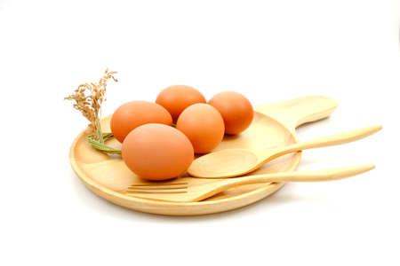 Five egg on wooden plate with wooden spoon, wooden fork and dried grass flowers