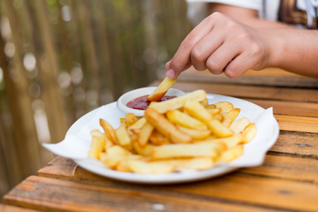hand holding french fries dip to tomato sauce.の写真素材