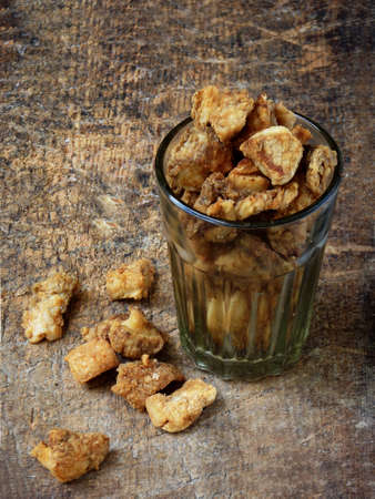 Homemade pork crackling, scratchings, various fried bacon in glass on wooden background. selective focusの写真素材