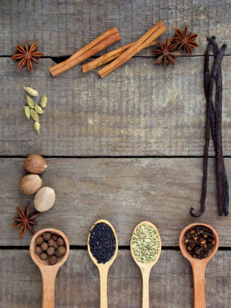composition of spices on wooden background: allspice, cloves, fennel, star anise, vanilla, cinnamon, green cardamom, nutmeg, black sesame. View from above. copy spaceの写真素材