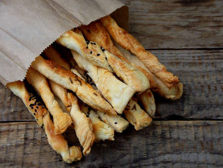 salty sticks of puff pastry sprinkled with cumin and Nigella on a wooden background