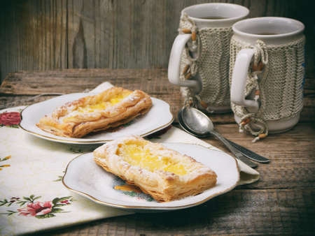 puff pastry with custard and a cup of tea on a wooden background. selective focusの写真素材
