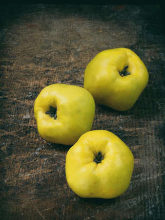 Three ripe yellow quince on a wooden backgroundの写真素材
