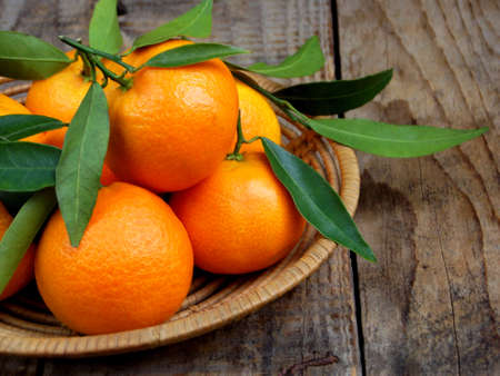 Ripe tangerines in the basket on wooden background. selective focus.の写真素材